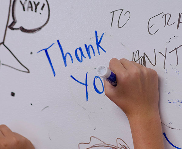 detail photo of a child writing 'thank you' on a ZURB whiteboard wall